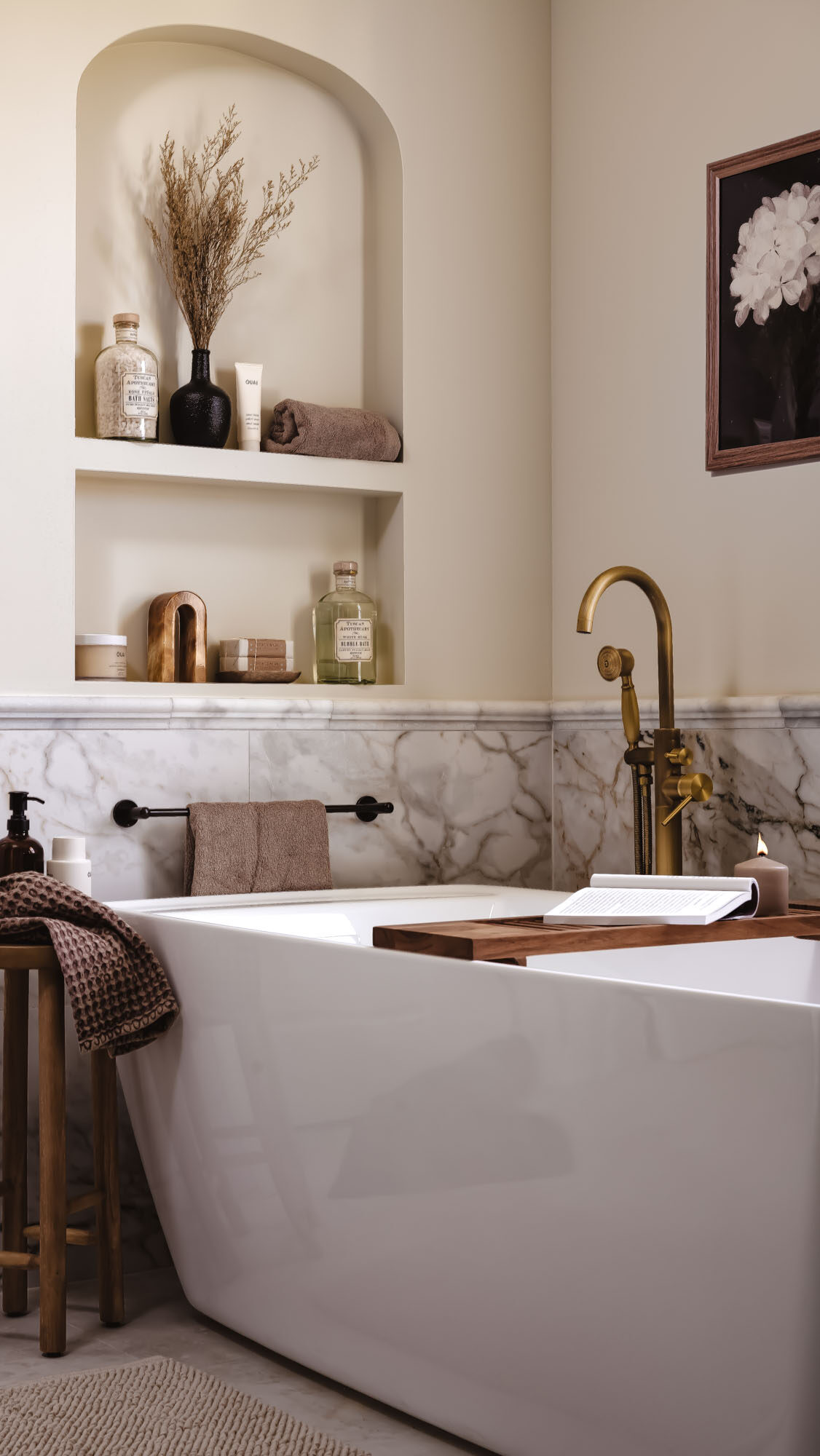 Warm neutral bathroom materials palette with honed stone and aged brass fixtures Warm neutral bathroom materials palette with honed stone, arched niches, and aged brass fixtures